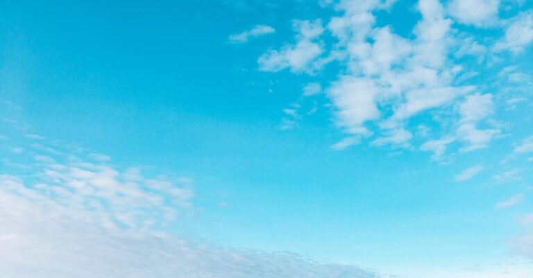 Tranquil scene of a lone walker on Colwyn Bay beach under a vast blue sky.